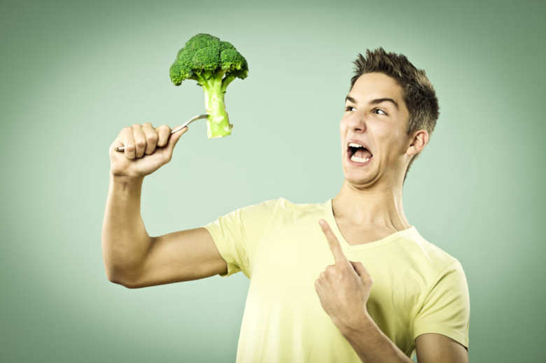 Unhappy boy with a broccoli