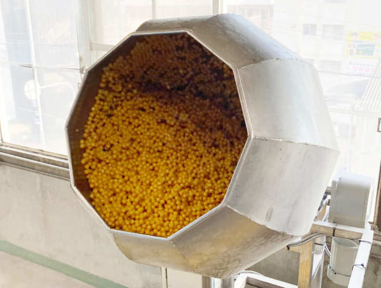 味つけの工程。チューリップのような機械の中でひなあられを撹拌させながらそれぞれの味をつけていく