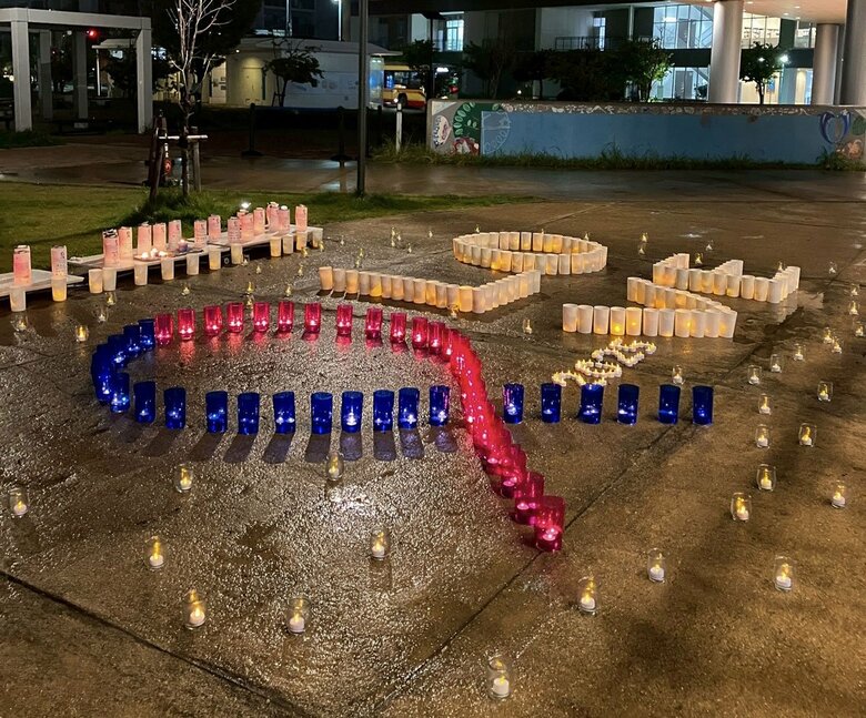 啓発週間のシンボル「ピンク＆ブルーリボン」の形に照らされたキャンドル