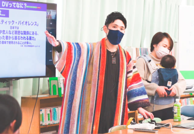 アイアイちゃんを連れて中学校で講演する守屋さん夫婦