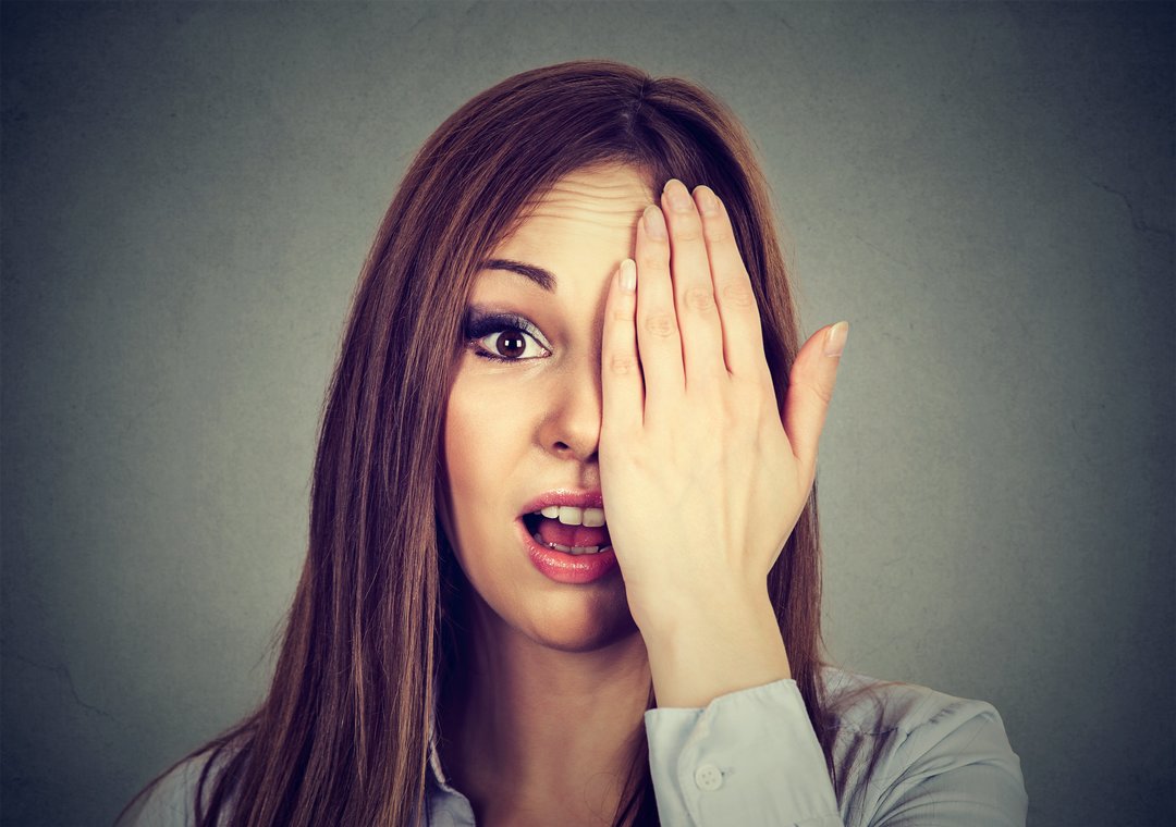 Surprised woman covering her eye with hand