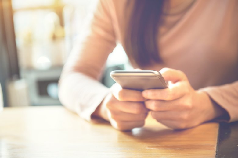 Woman using smartphone at modern coffee shop.