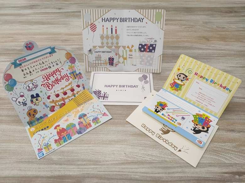 グループ会社の一部で導入している「アニバーサリーお祝い制度」では、社員の誕生日に「図書券」など、社員の子どもの誕生日には「こども商品券」が贈られる。（左）株式会社BANDAI SPIRITSの社長から社員の子どもにあてた誕生日カードとこども商品券。（中央）株式会社バンダイの社長から社員にあてた誕生日カードと図書カード。（右）株式会社バンダイナムコビジネスアークの社長から社員にあてた図書カード　©BANDAI,WiZ