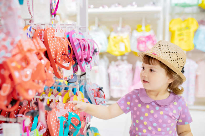 Cute little girl choosing clothes in the shop