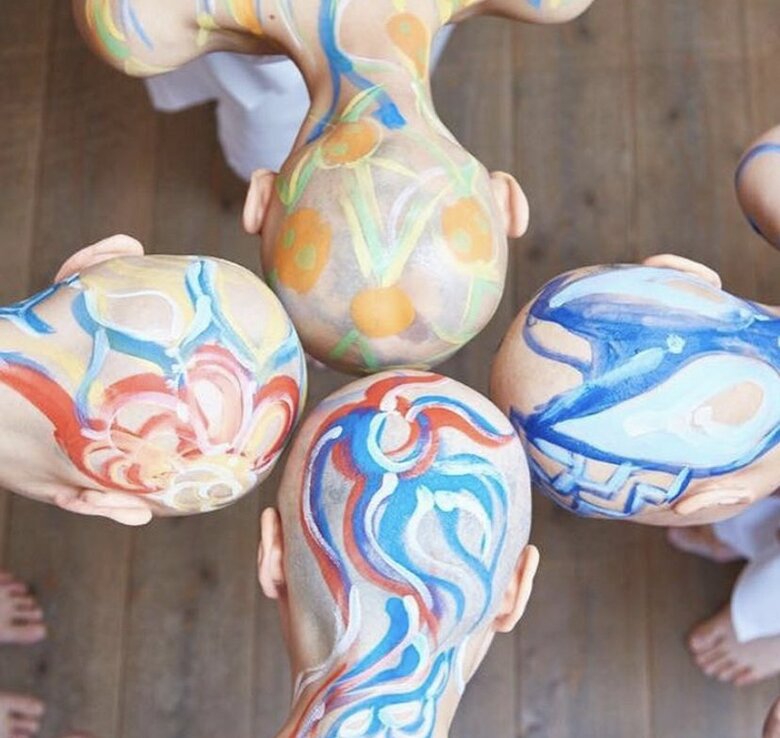 スキンヘッドでパフォーマンスをする仲間たちとペイティングをほどこす