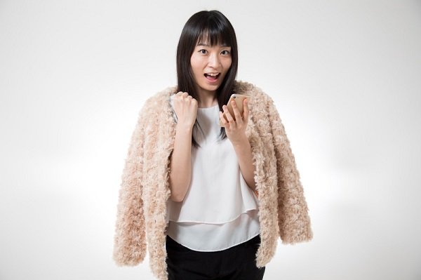 フリマアプリを見てはしゃぐ女性の画像