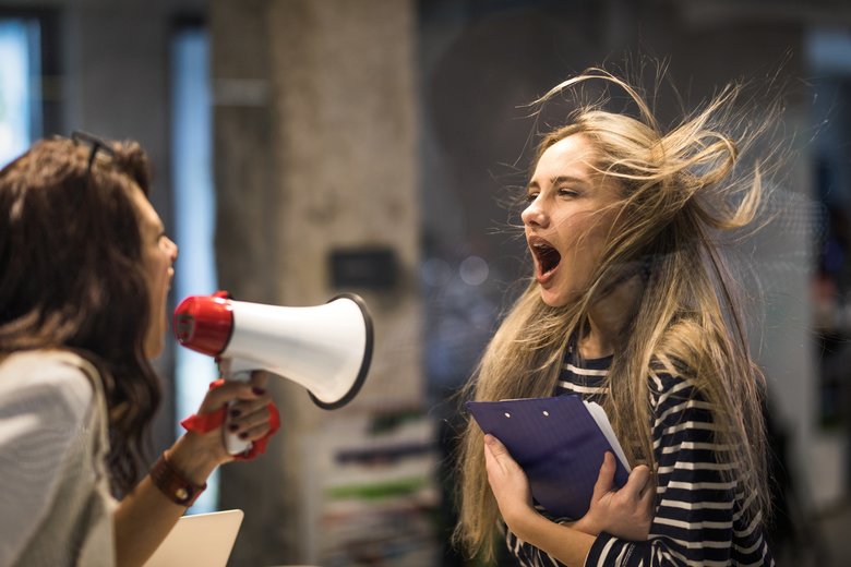 Angry female manager yelling at her colleague through megaphone.