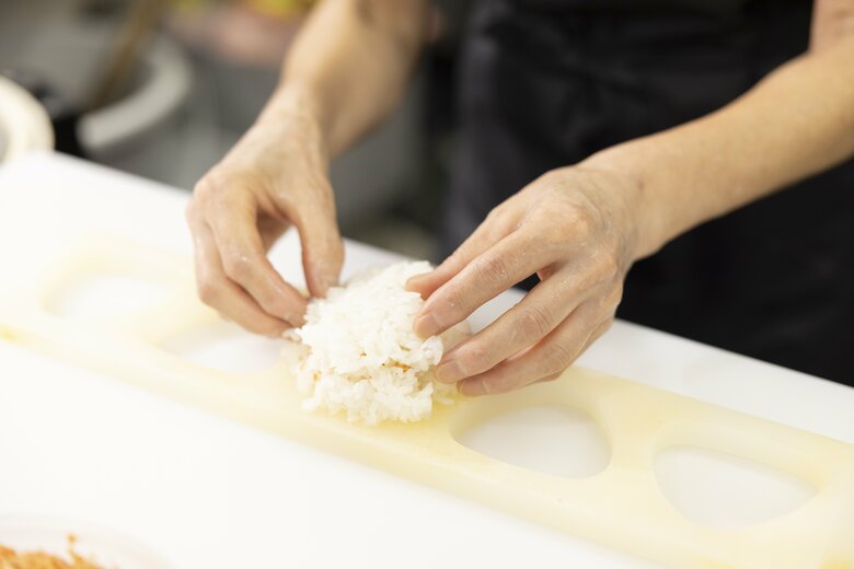 8／具がはみ出さないよう、おにぎりの端を指先で軽く押さえる