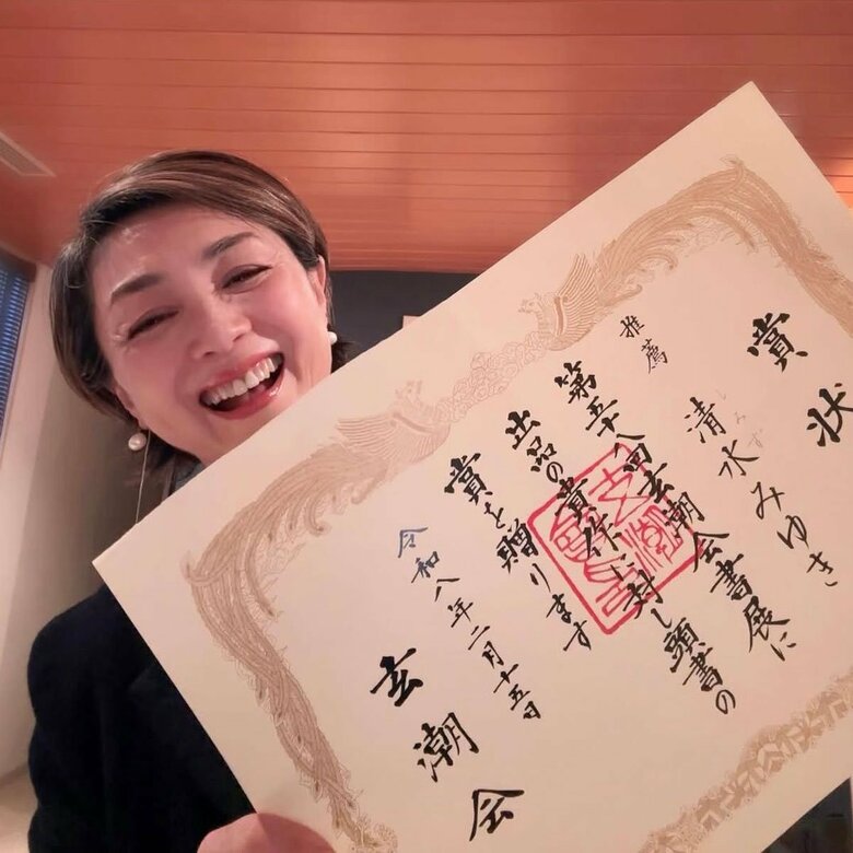 書展でもらった賞状を両手にして笑顔の香坂さん