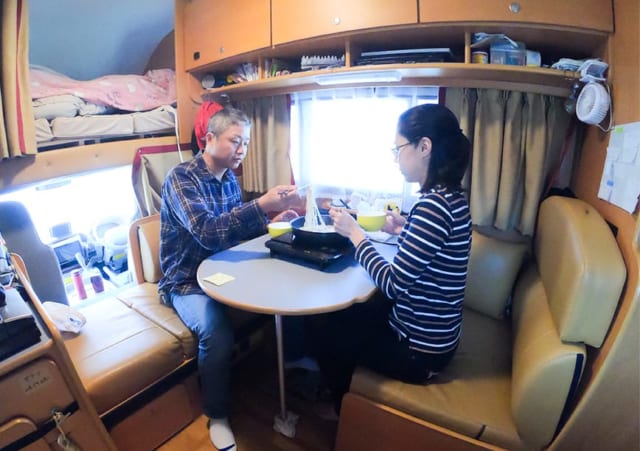 キャンピングカー内で食事をするむっちゃんとがっちゃん。左上はバンクベッド