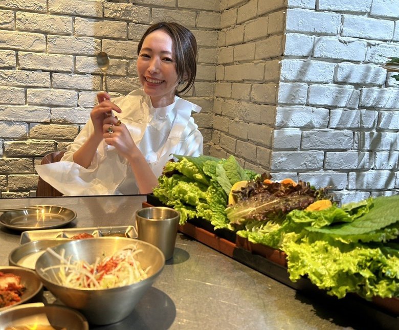 彦坂さんの近影。韓国焼肉を前にはじけるような笑顔で