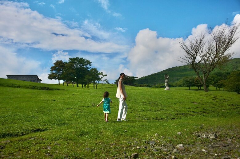 青い空の下、緑の草原で遊ぶ森さんとお子さん。自然豊かな場所を訪れることも多いそう
