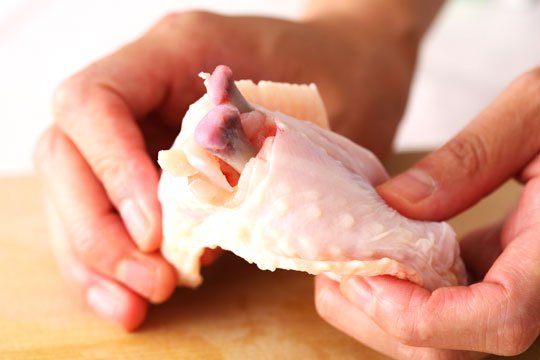 切り込みが入った手羽先を両手でしっかりと持ち、両手で関節部分を折るようにして2本の骨をむき出しにする。