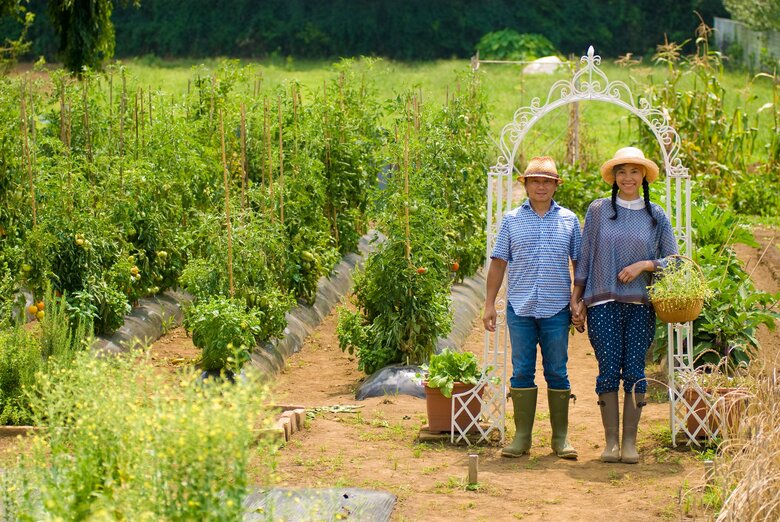家庭菜園をバックに林マヤさんご夫婦