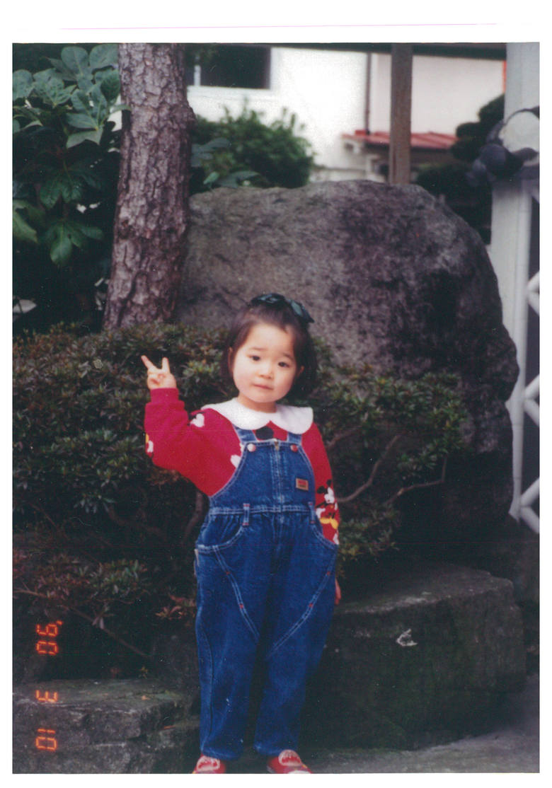 赤いセーターを着てピース、川嶋さん3歳くらいの頃