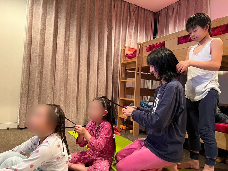 お風呂から上がってくつろぎの時間。髪の毛を結び合う娘さんと息子さん