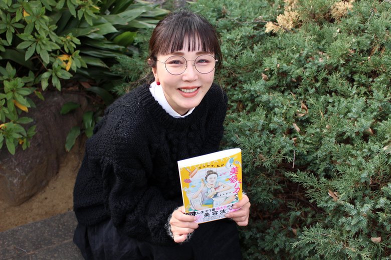 新著を手に笑顔のまんきつさん。家にいるときはしょっちゅう妄想の世界に浸っているそう