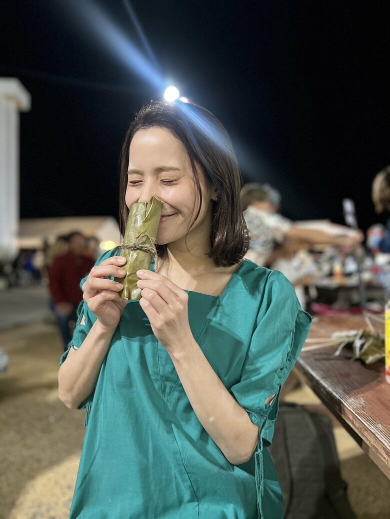 座間味島のお祭りで月桃の葉で包んだ香りのいいお餅「カーサームーチー」を手にする比嘉梨乃さん
