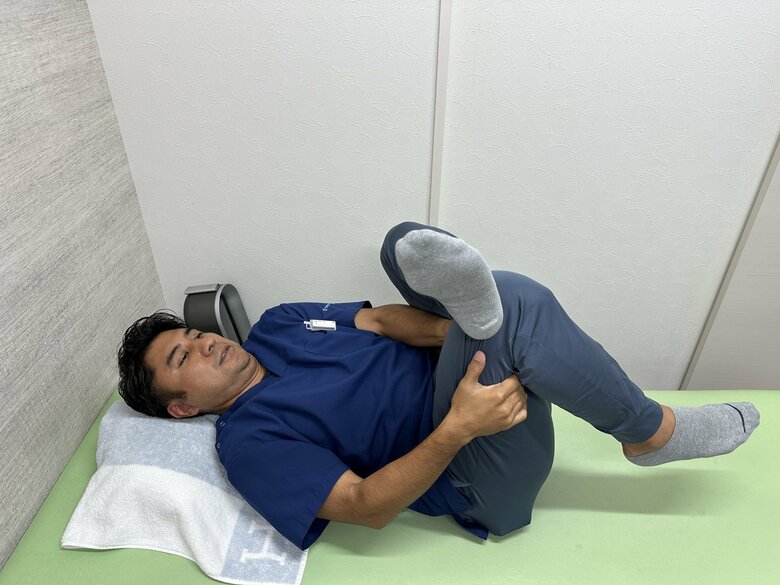 成長痛や足の痛みを防ぐストレッチ③仰向けに寝た状態で、左足を右膝に乗せる。右の太ももを左右の腕でつかみ、お尻の筋肉をストレッチ。反対側も同様に