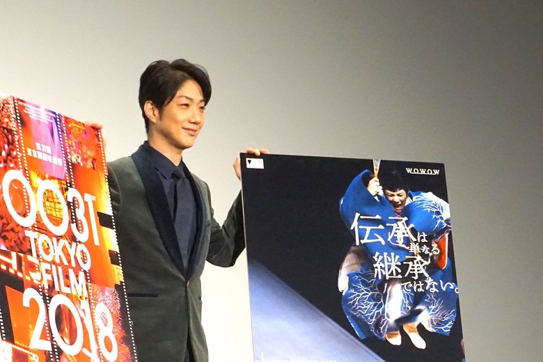 ポスターと一緒に笑顔を浮かべる萬斎さん