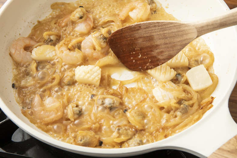 フライパンにバターとおろしにんにくを入れて中火で熱し、玉ねぎを入れて5分ほど炒める。途中で塩少々（分量外）をふり、全体が薄い茶色になったらシーフードミックスとみりんを加えて強火にし、アルコールを飛ばしながら1分ほど炒める。水300ml（分量外）とアスパラを加えて沸いてきたら中火にし、1分ほど煮る。カレールーを入れて溶かし、とろみがついたら火を止める。