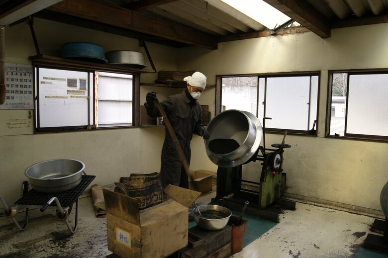 花火の玉に詰める火薬を釜で作る作業風景。色が違う火薬をかけていく