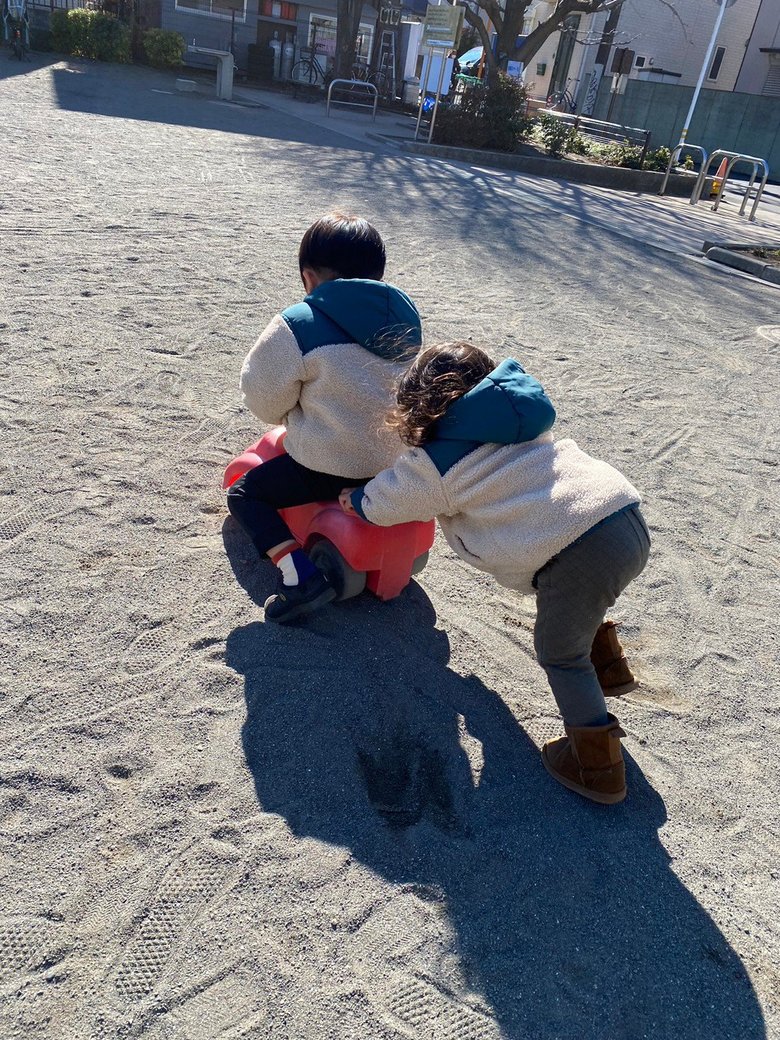 おそろいの洋服で、公園にある子ども用の車で仲良く遊ぶきょうだい
