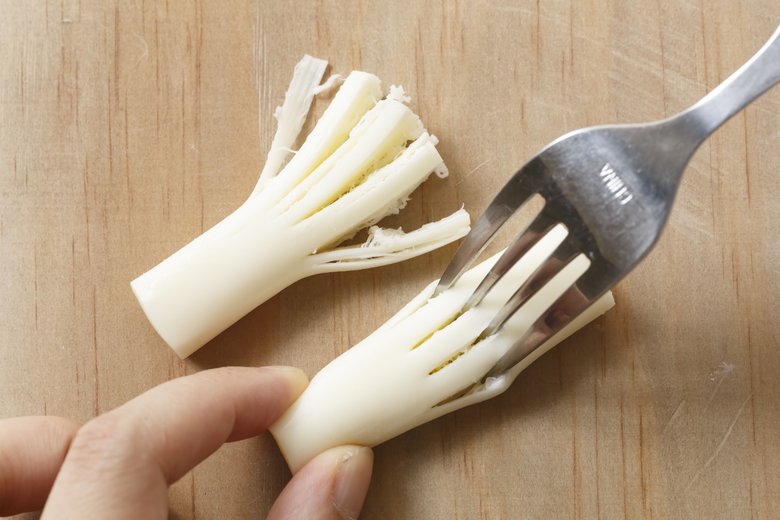 さけるチーズの下半分をフォークで回転させてさいた部分の幅が均等になるように４回くらいさく。反対側に軽く穴をあけ、プリッツをさしこむ。かにかまの赤い部分を巻きつけて、ホウキに見立てて、でき上がり！