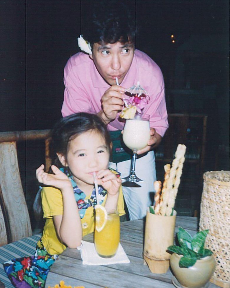 アイドルみたい！イエローの鮮やかなブラウス姿でジュースを飲む幼少期の関根さん