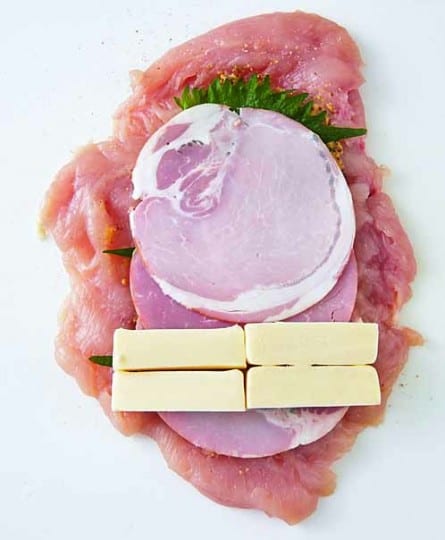 ①を縦長に置いて、塩、こしょうをふり、粒マスタードを半量ずつ塗る。青じそ半量ずつを少しずつずらして重ねてのせ、上にハムを同様にのせる。手前に半分にカットしたチーズを横に半量ずつ並べて置く。両端を内側に折り、くるくると巻いて、広げたラップにのせ、全体をふんわり包む。
※鶏胸肉はパサつきがちなので、薄くのばしてから具をのせ厚みを均一にすると、加熱時間が短くなり、パサつきを防いでしっとり仕上がる。